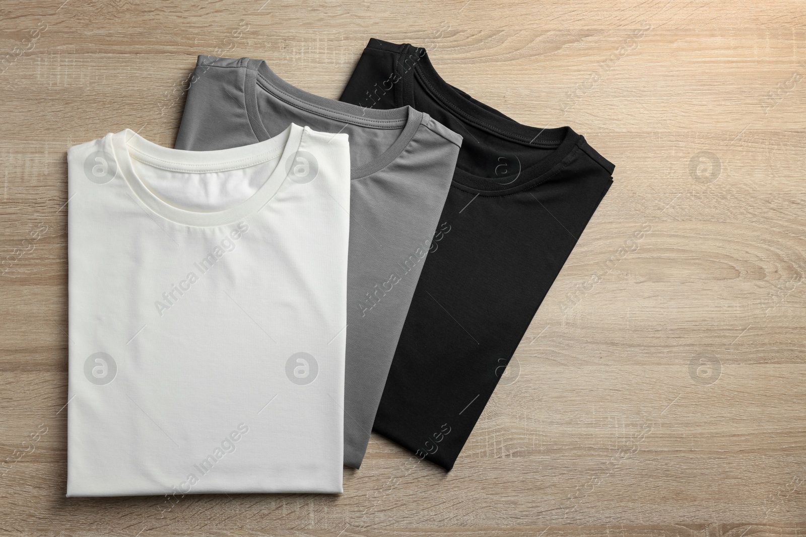 Photo of Blank t-shirts on wooden background, flat lay. Mockup for design