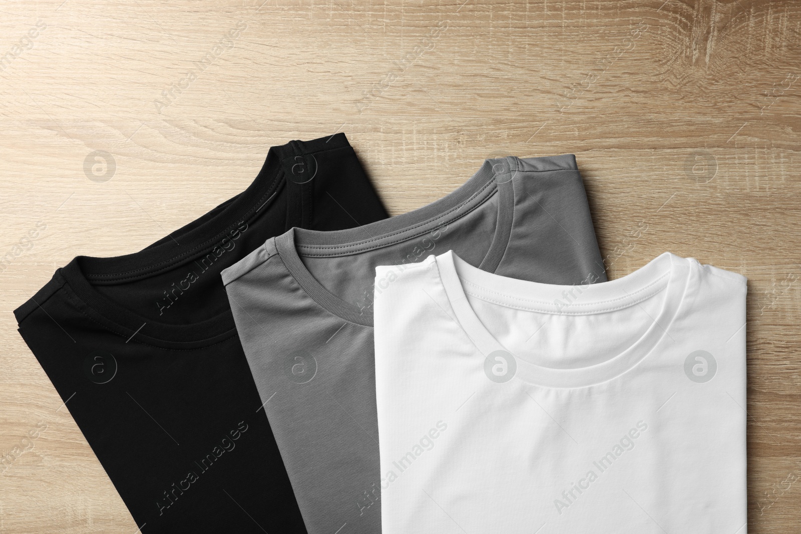 Photo of Blank t-shirts on wooden background, flat lay. Mockup for design