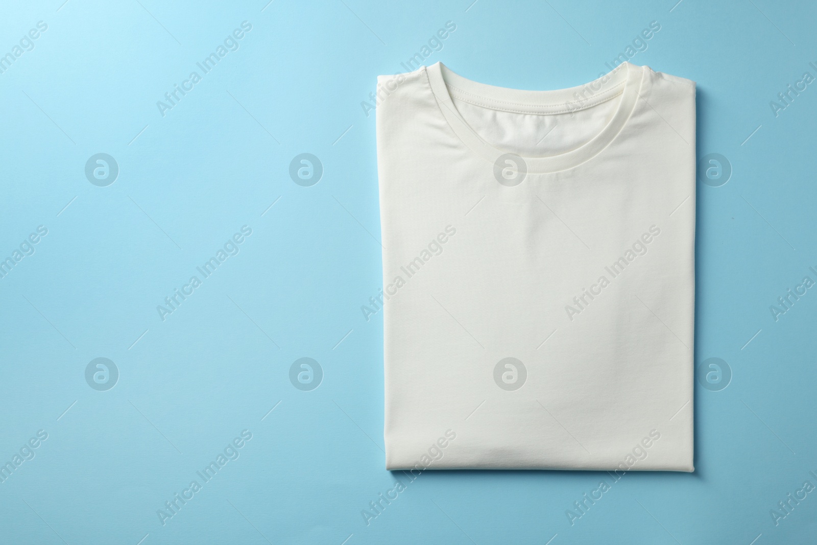 Photo of One blank t-shirt on light blue background, top view. Mockup for design