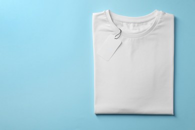 Photo of One blank t-shirt on light blue background, top view. Mockup for design