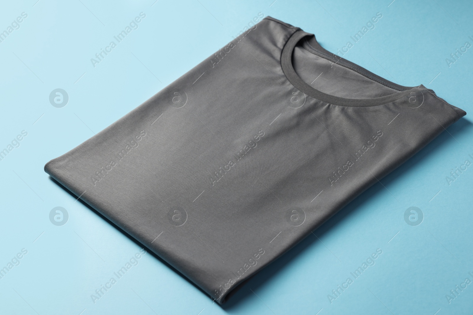 Photo of One blank t-shirt on light blue background, closeup. Mockup for design