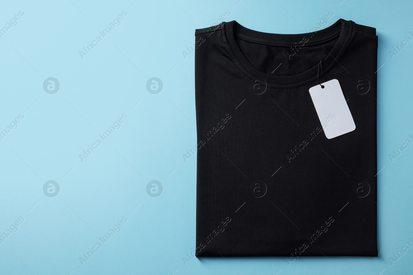 Photo of One blank t-shirt on light blue background, top view. Mockup for design