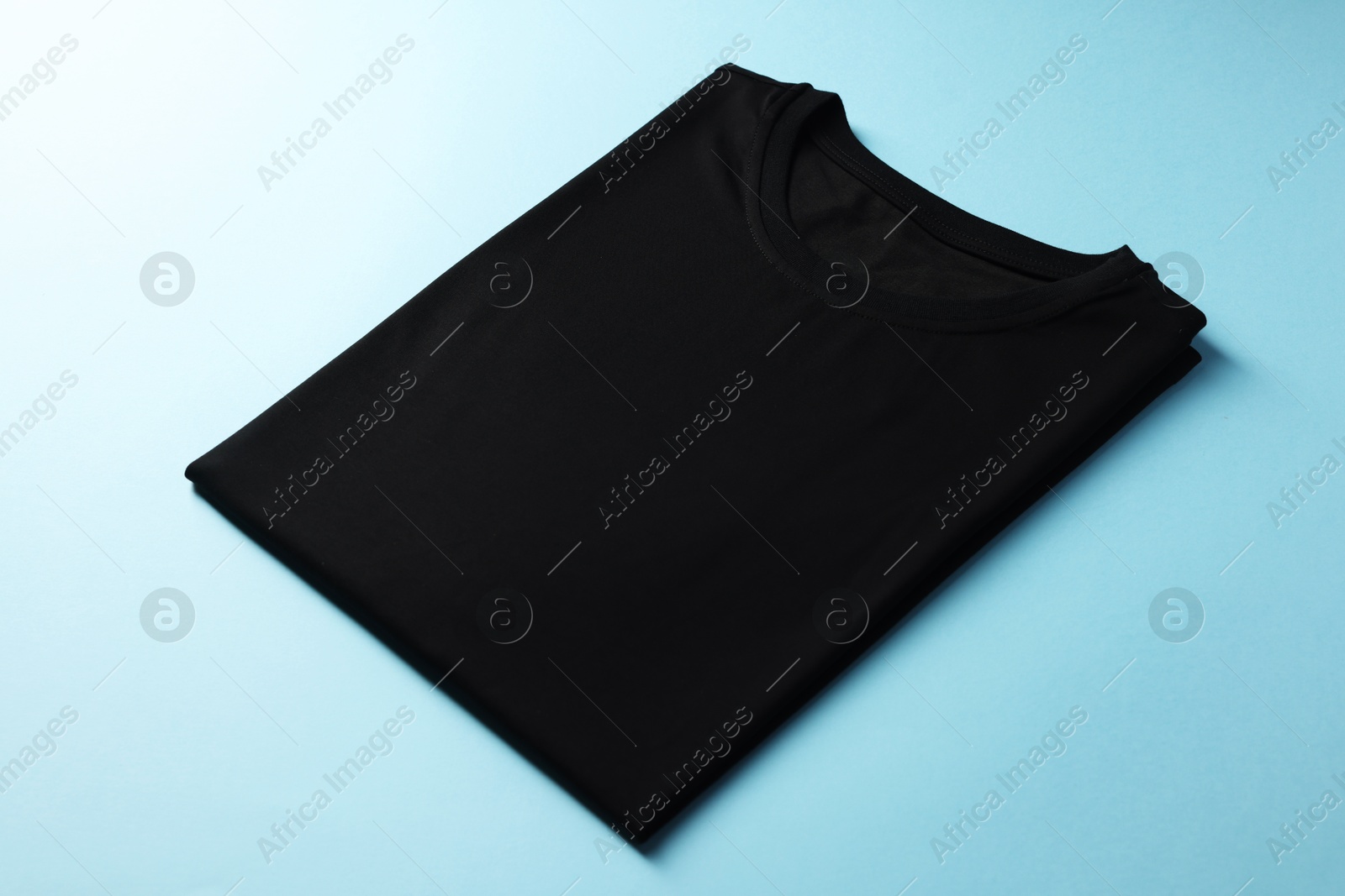 Photo of One blank t-shirt on light blue background, closeup. Mockup for design