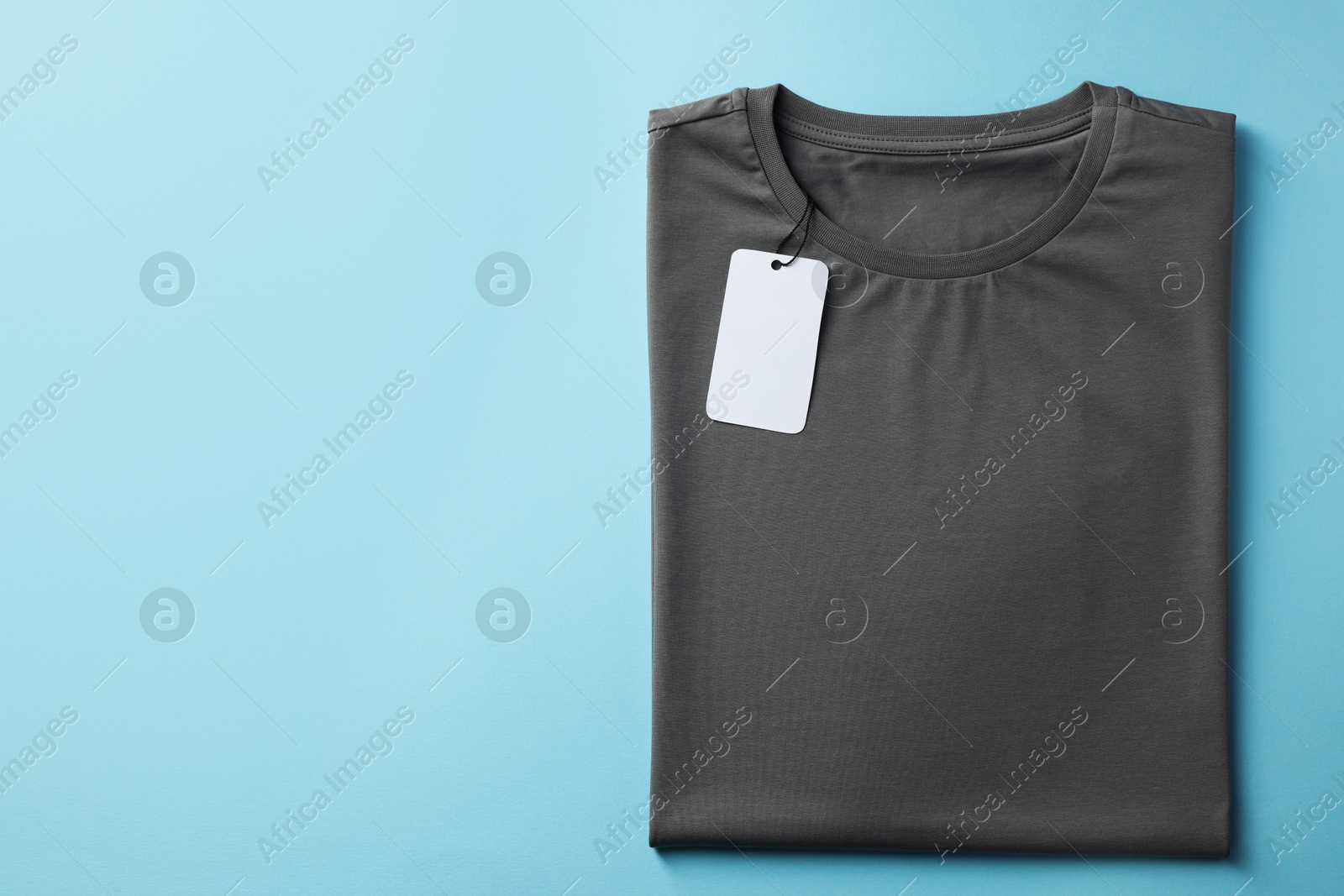 Photo of One blank t-shirt on light blue background, top view. Mockup for design