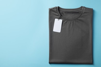 One blank t-shirt on light blue background, top view. Mockup for design