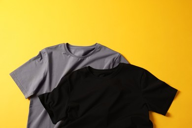 Photo of Blank t-shirts on yellow background, flat lay. Mockup for design