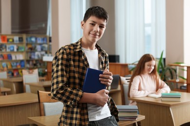 Photo of Boy with book near desk in public library