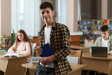 Photo of Boy with book near desk in public library