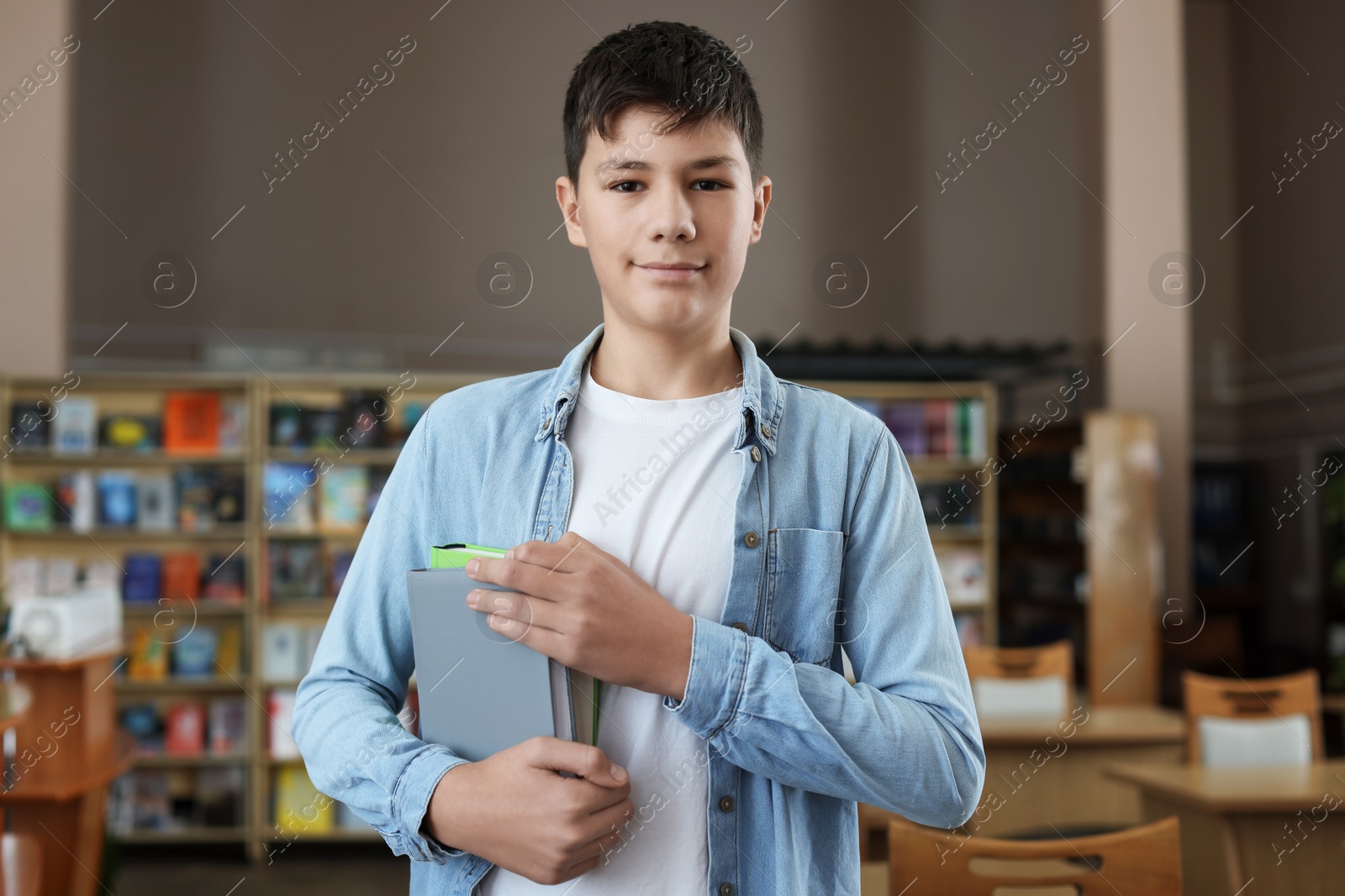 Photo of Handsome boy with books in public library