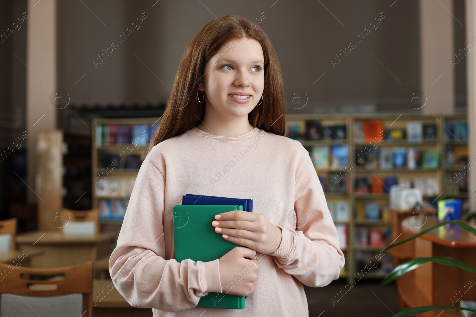 Photo of Beautiful girl with books in public library