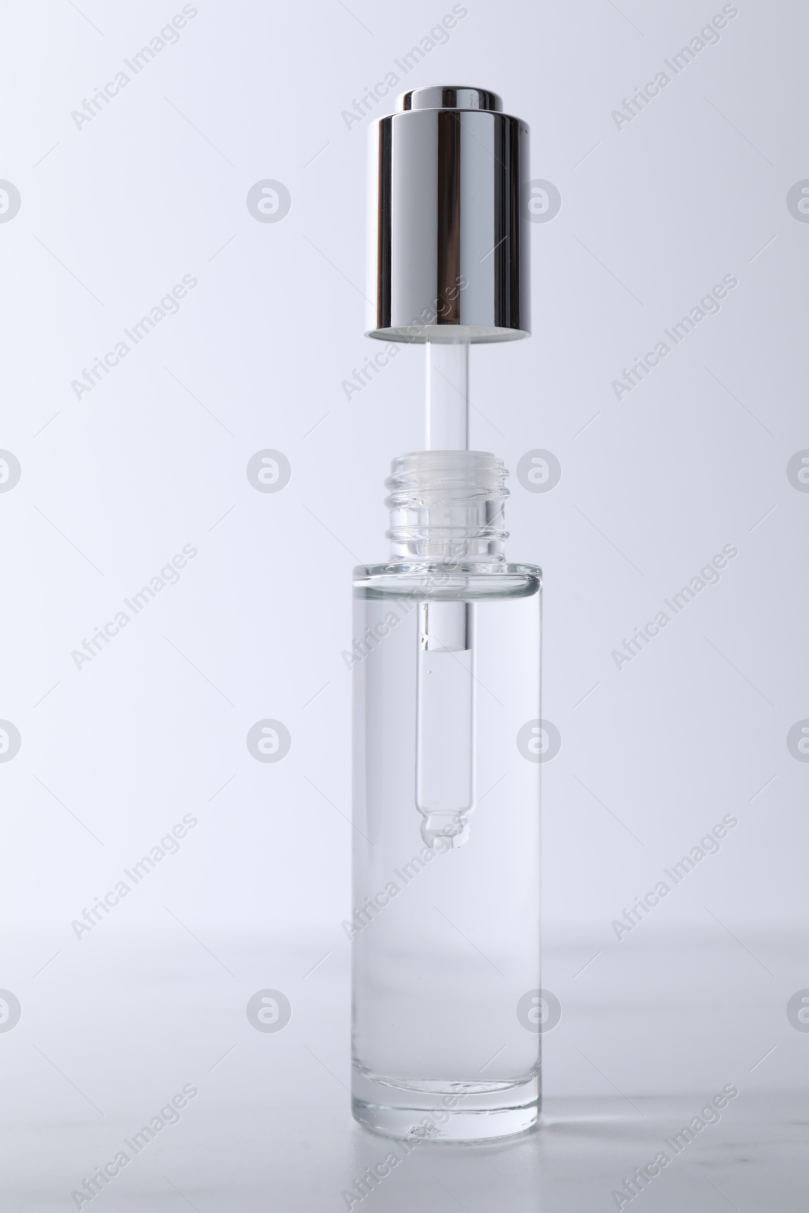 Photo of Bottle and pipette of serum on light grey table, closeup