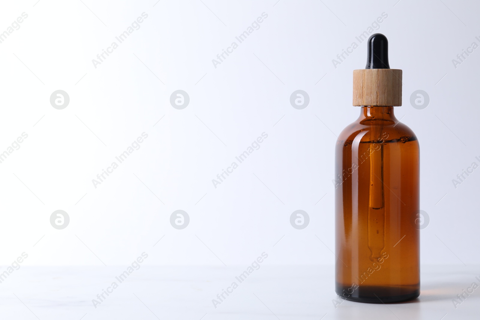 Photo of Bottle of serum on light table, closeup. Space for text