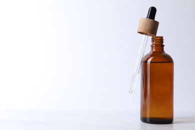 Bottle and pipette of serum on light table, closeup. Space for text