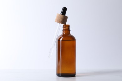 Bottle and pipette of serum on light table, closeup