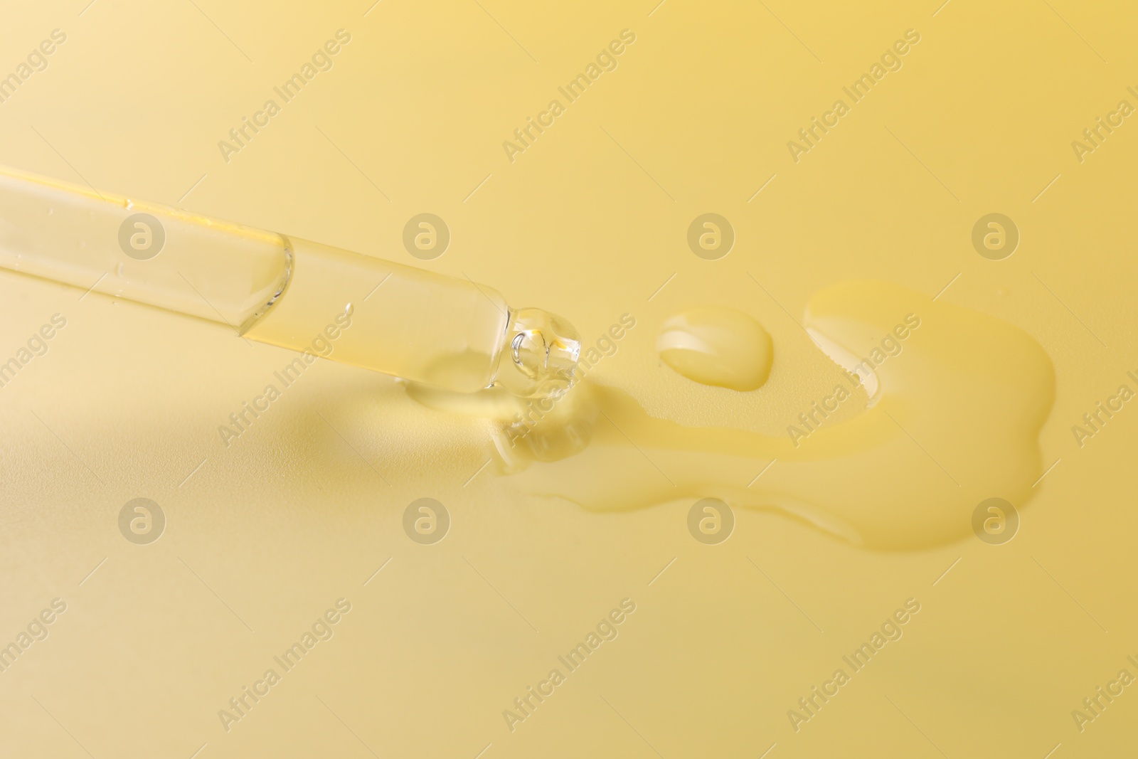 Photo of Pipette with serum on yellow background, closeup