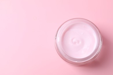 Photo of Jar of moisturizing cream on pink background, top view. Space for text