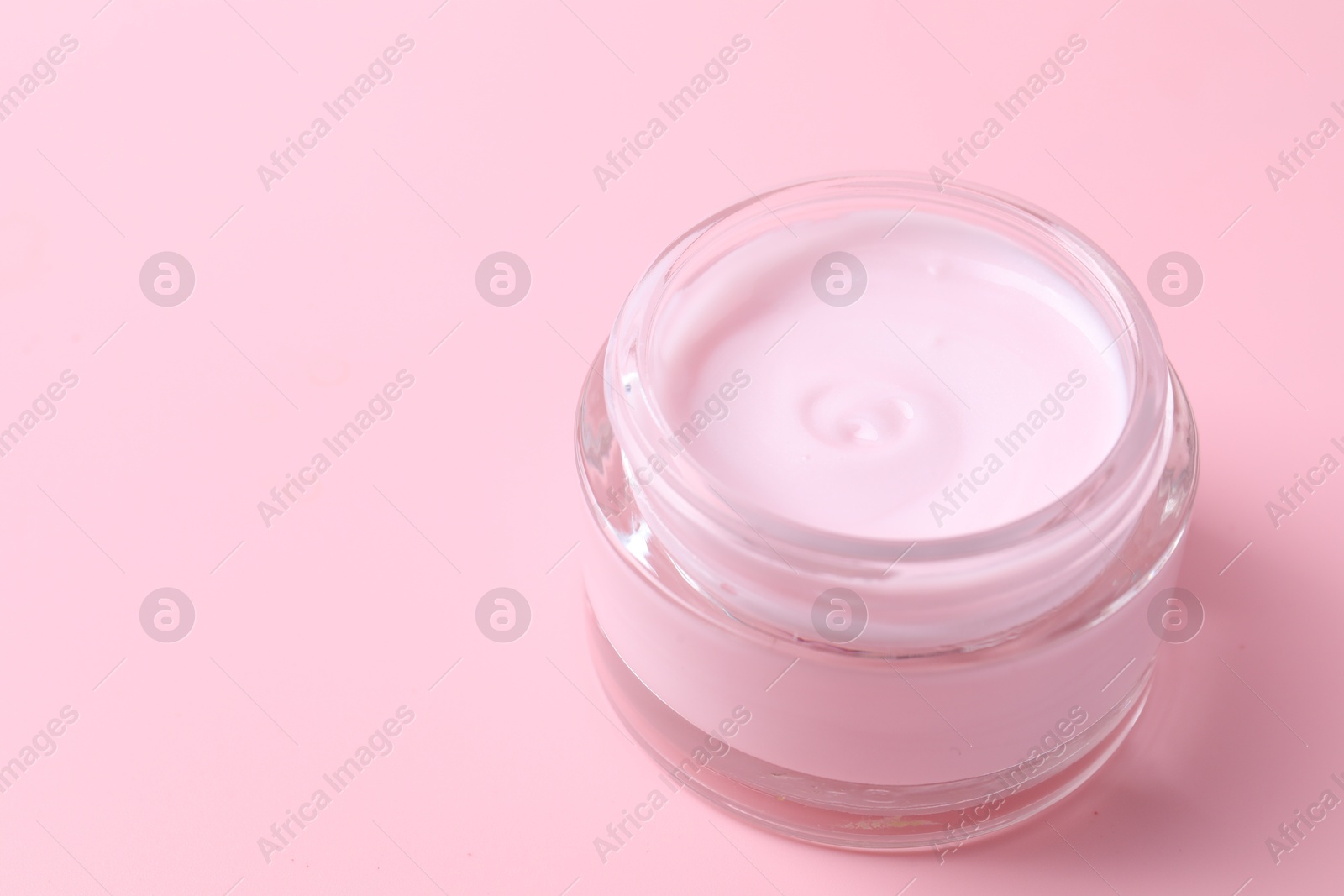 Photo of Jar of moisturizing cream on pink background, closeup. Space for text