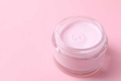 Photo of Jar of moisturizing cream on pink background, closeup. Space for text