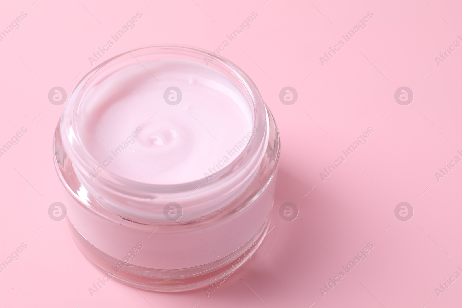 Photo of Jar of moisturizing cream on pink background, closeup. Space for text