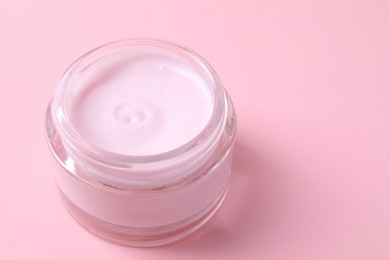 Photo of Jar of moisturizing cream on pink background, closeup. Space for text