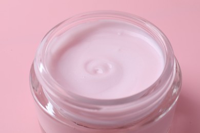 Jar of moisturizing cream on pink background, closeup