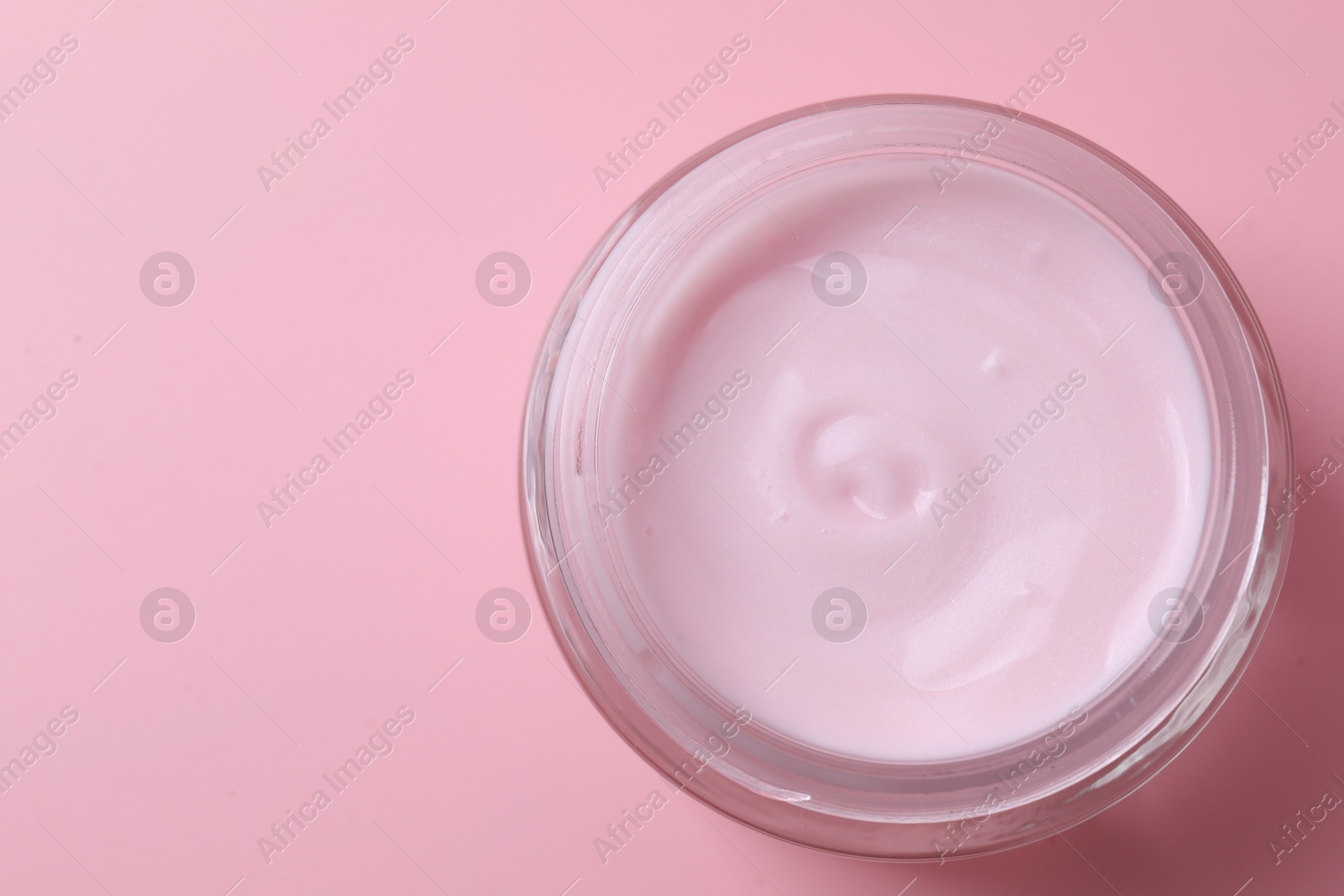 Photo of Jar of moisturizing cream on pink background, top view. Space for text