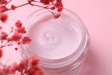 Photo of Jar of moisturizing cream and gypsophila flowers on pink background, closeup