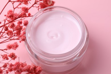 Jar of moisturizing cream and gypsophila flowers on pink background, closeup