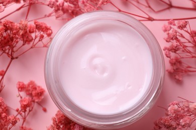 Photo of Jar of moisturizing cream among gypsophila flowers on pink background, flat lay