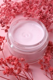 Jar of moisturizing cream and gypsophila flowers on pink background, closeup