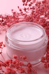 Photo of Jar of moisturizing cream and gypsophila flowers on pink background, closeup