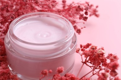 Photo of Jar of moisturizing cream and gypsophila flowers on pink background, closeup