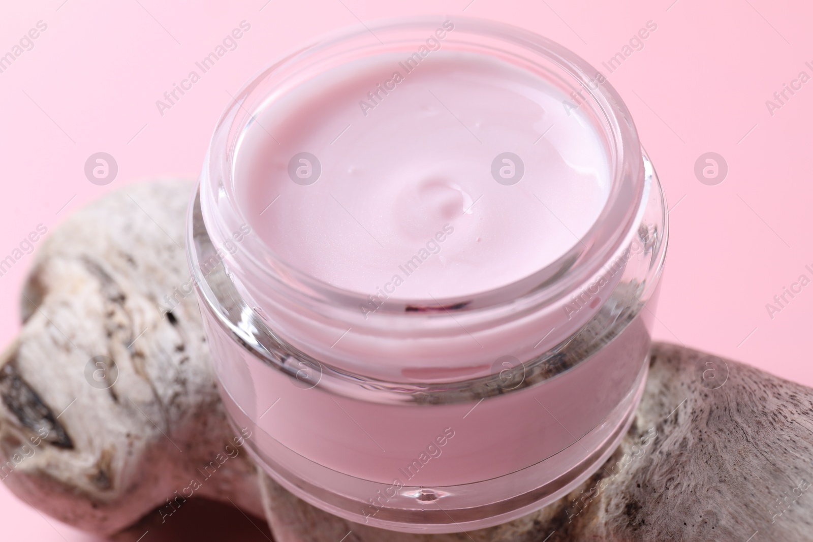 Photo of Jar of moisturizing cream and snag on pink background, closeup