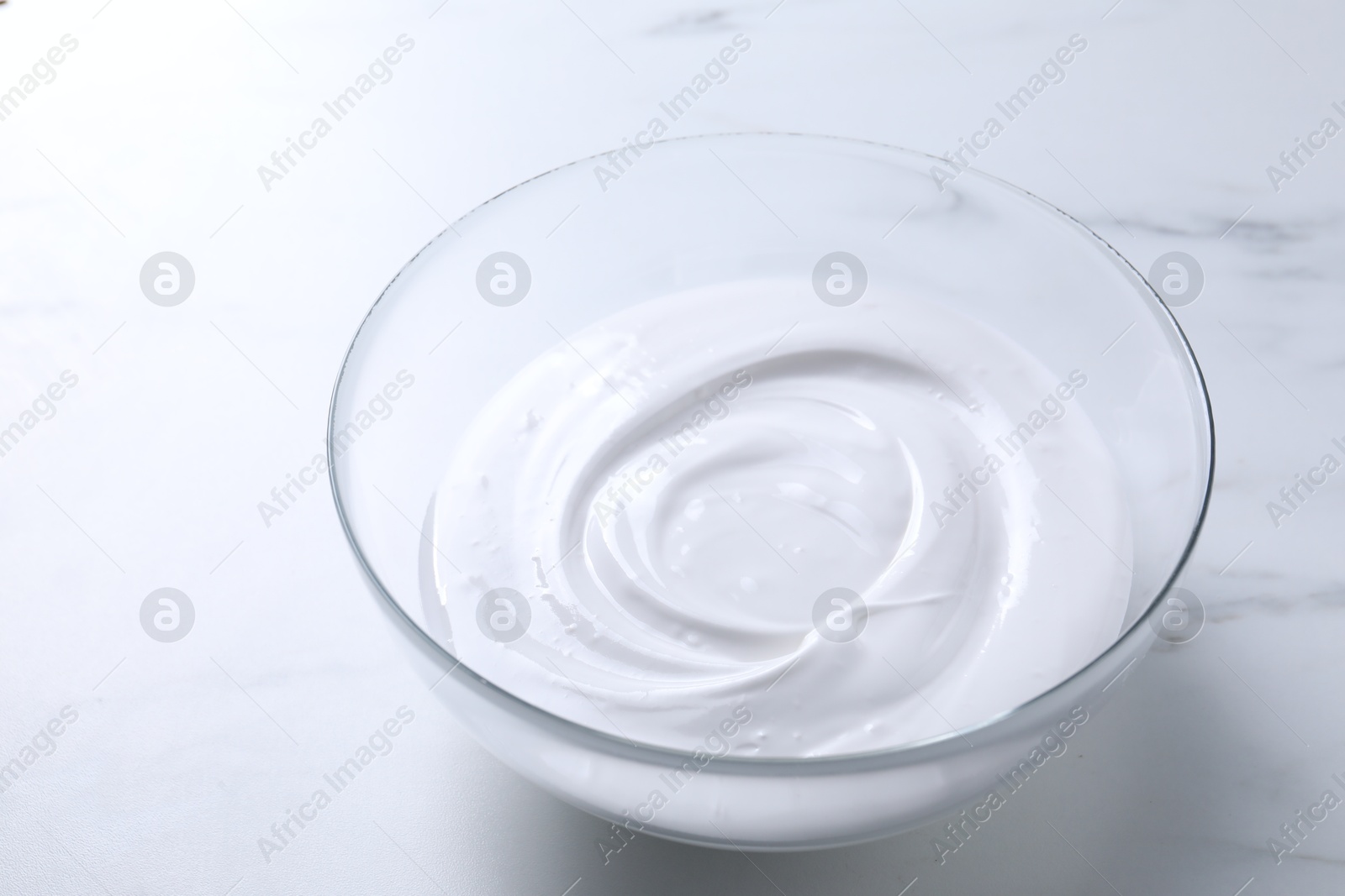 Photo of Bowl of whipped cream on white marble table