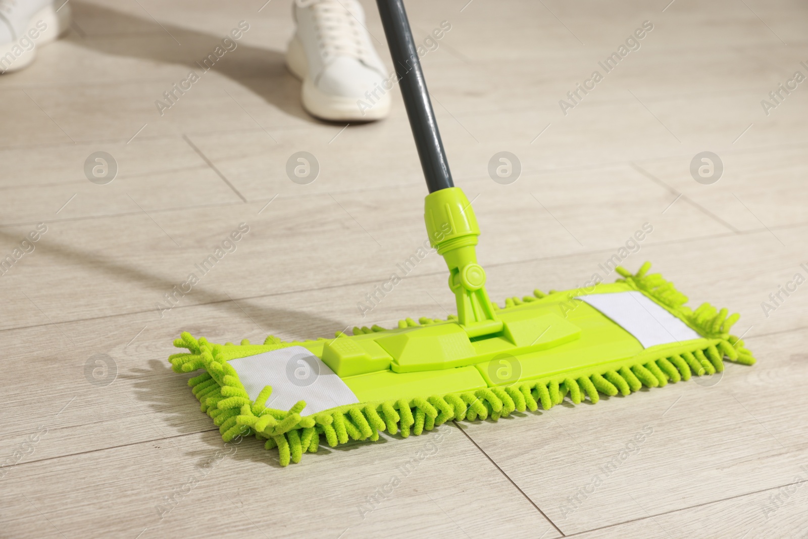 Photo of Woman cleaning floor with mop at home, closeup