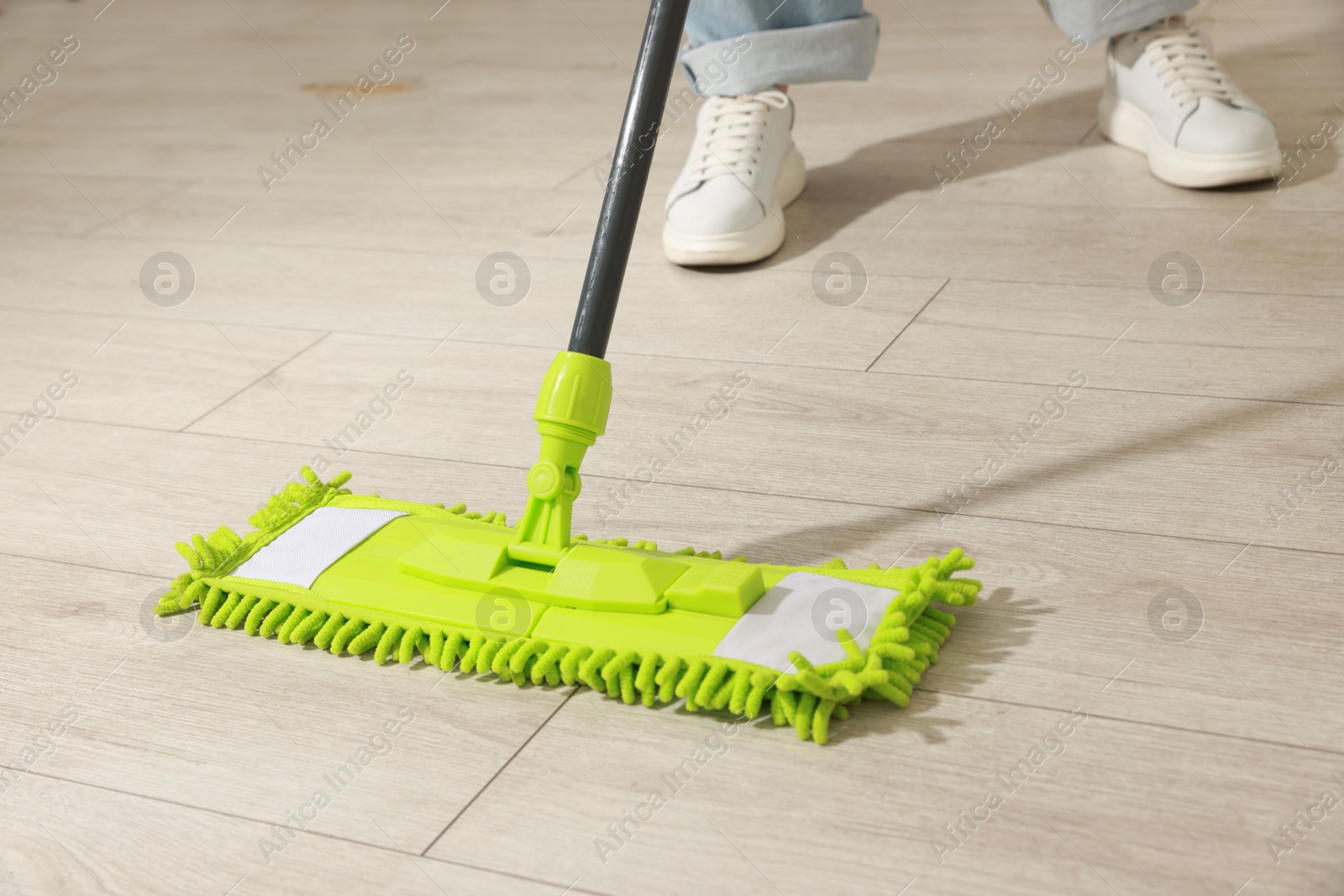 Photo of Woman cleaning floor with mop at home, closeup