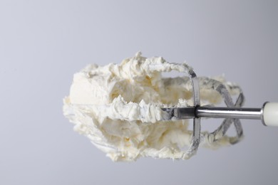 Photo of Whisks with whipped cream on white background, closeup