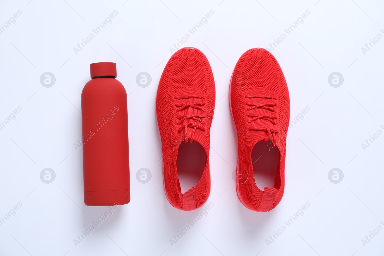 Photo of Sneakers and water bottle on white background, flat lay. Sports equipment