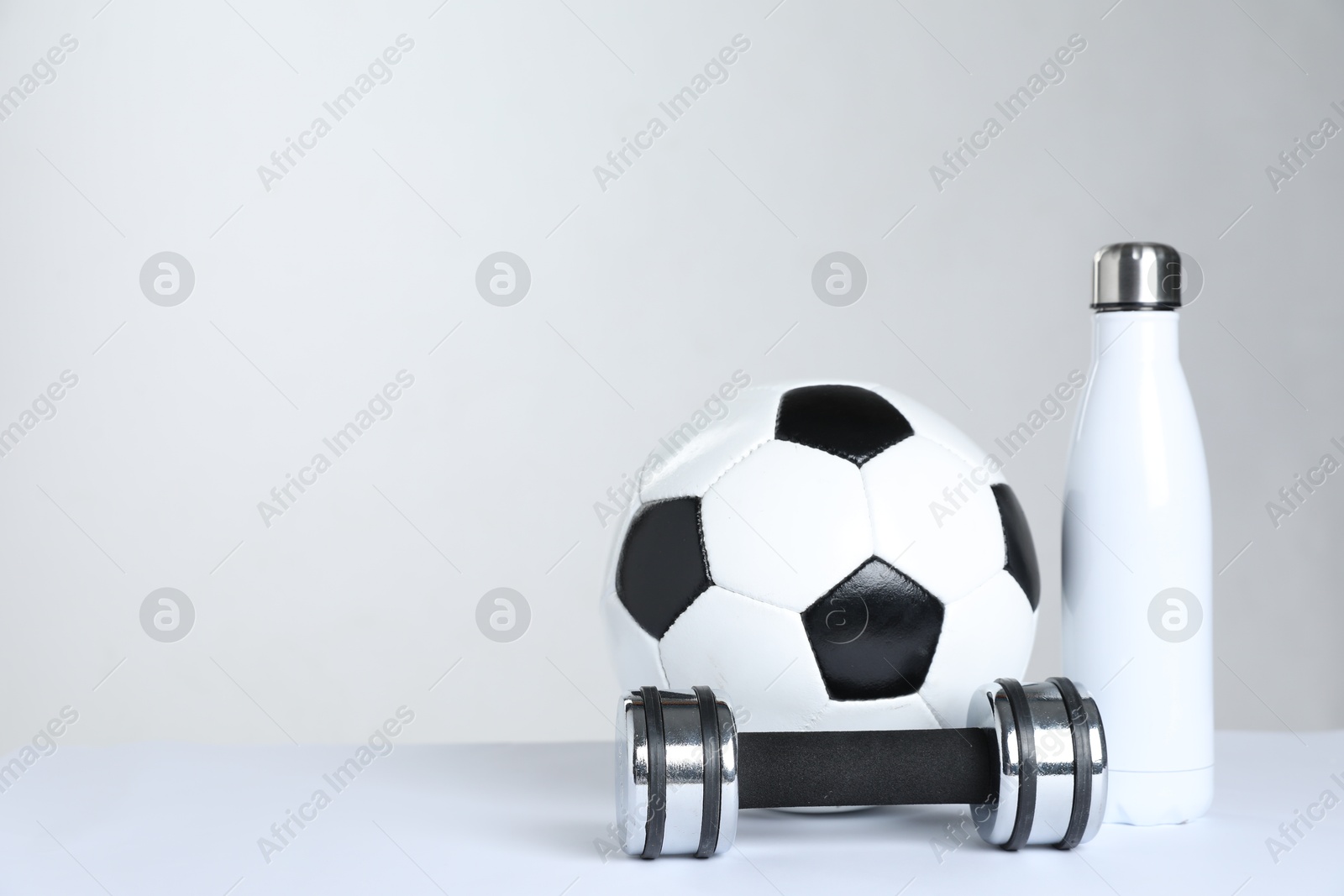 Photo of Dumbbell, water bottle and soccer ball on white background, space for text. Sports equipment