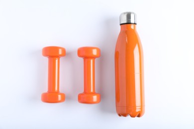 Photo of Dumbbells and water bottle on white background, flat lay. Sports equipment