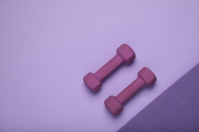 Photo of Purple dumbbells on color background, top view and space for text. Sports equipment