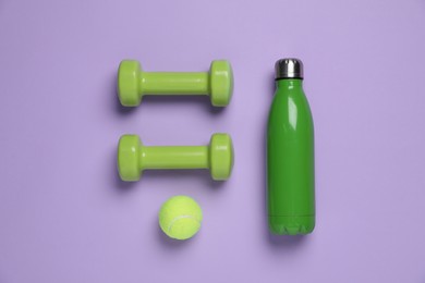 Photo of Water bottle, tennis ball and dumbbells on violet background, flat lay. Sports equipment