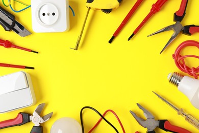 Photo of Frame of different electrical tools on yellow background, flat lay. Space for text