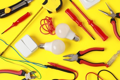 Photo of Different electrical tools on yellow background, flat lay