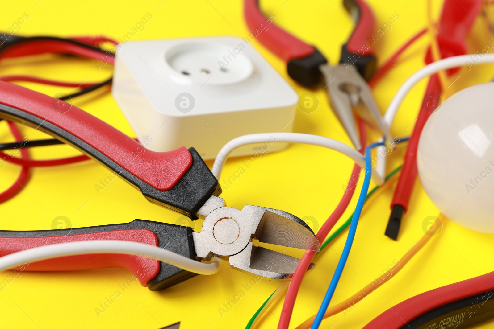 Photo of Different electrical tools on yellow background, closeup