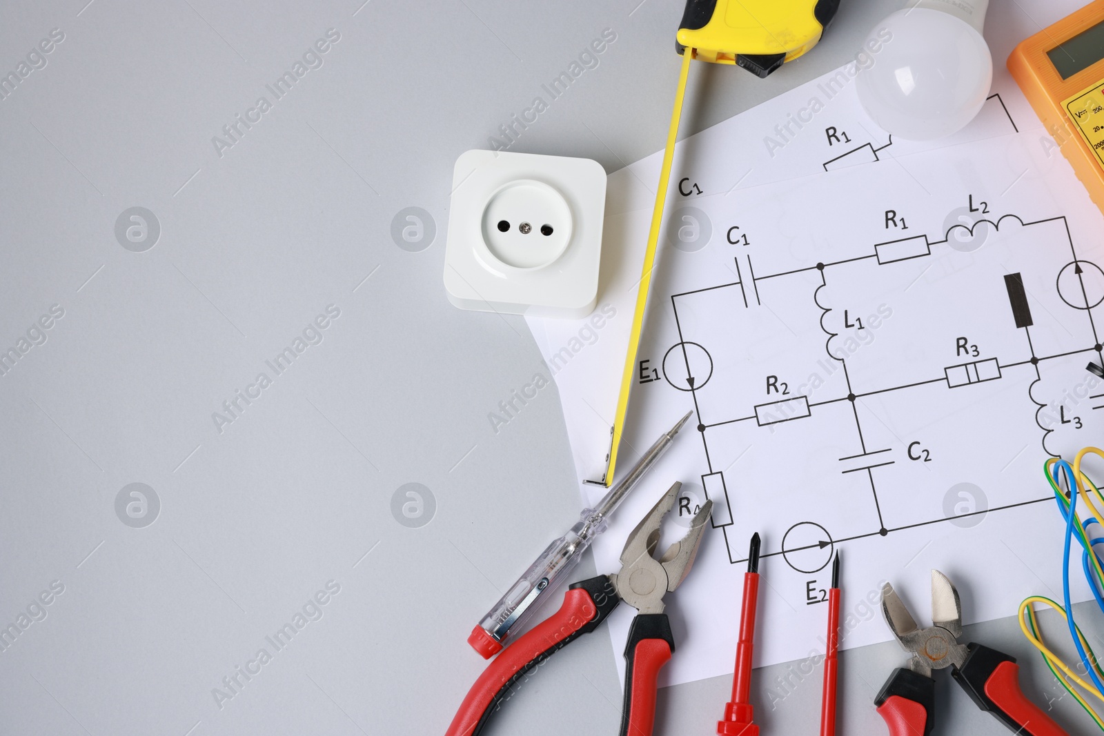 Photo of Different electrical tools and circuit diagram on grey background, flat lay. Space for text