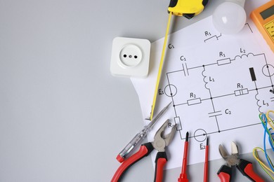 Photo of Different electrical tools and circuit diagram on grey background, flat lay. Space for text