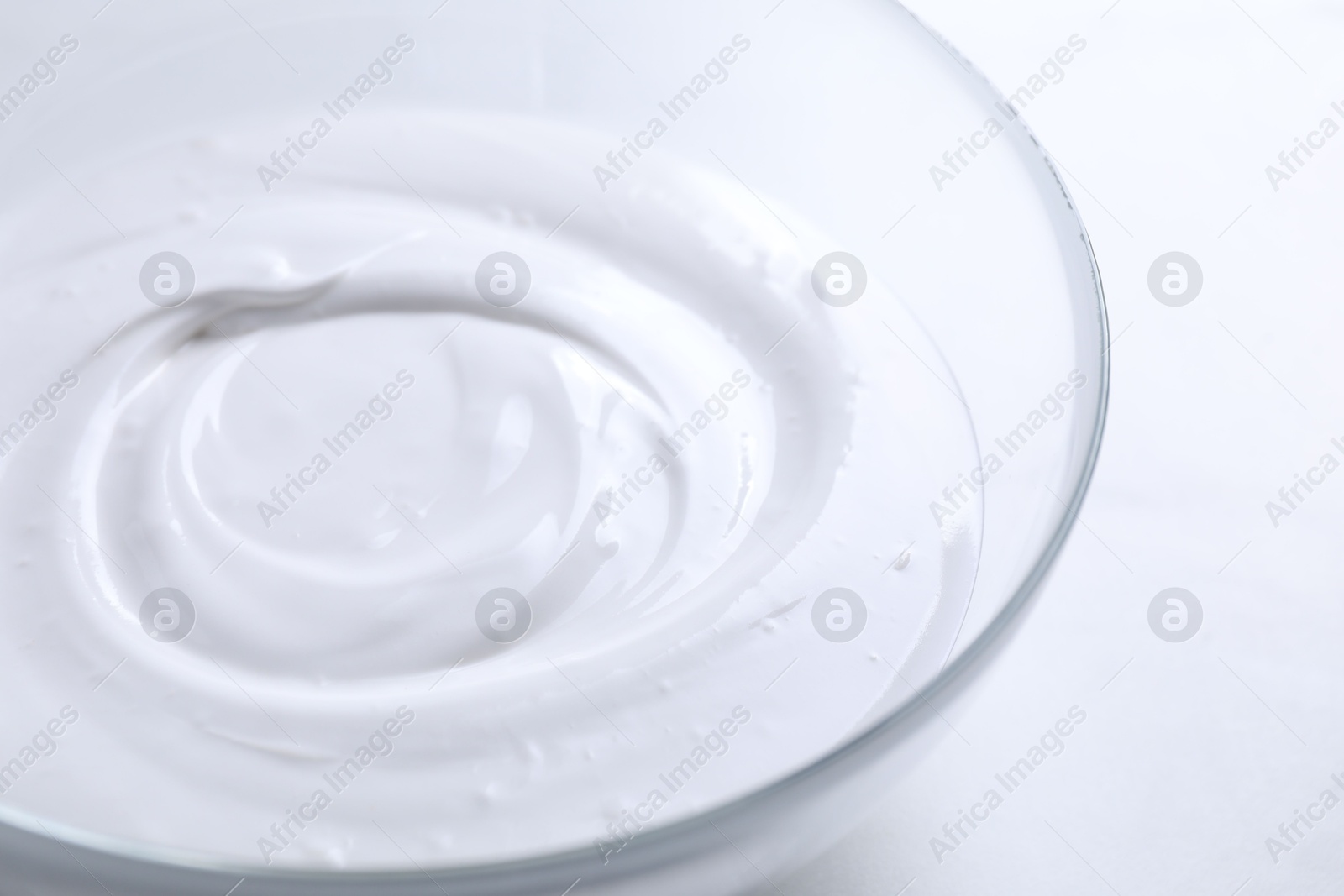 Photo of Bowl of whipped cream on white table, closeup