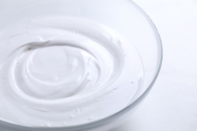 Photo of Bowl of whipped cream on white table, closeup