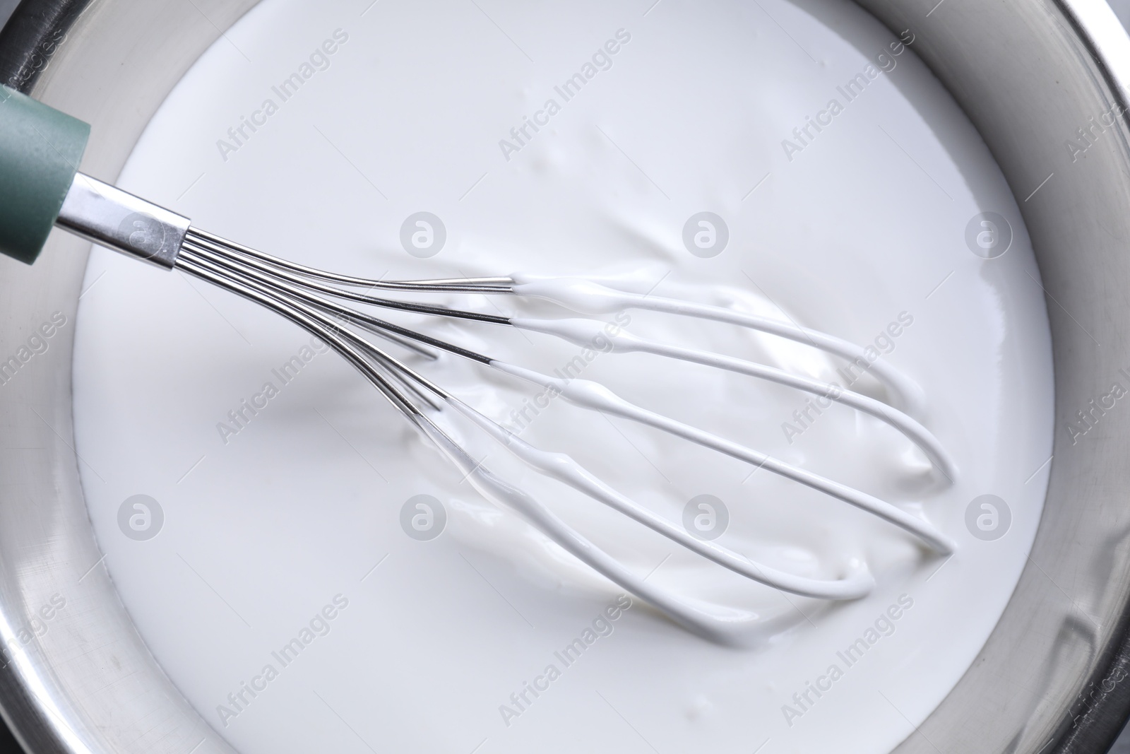 Photo of Whisk and whipped cream in bowl, top view